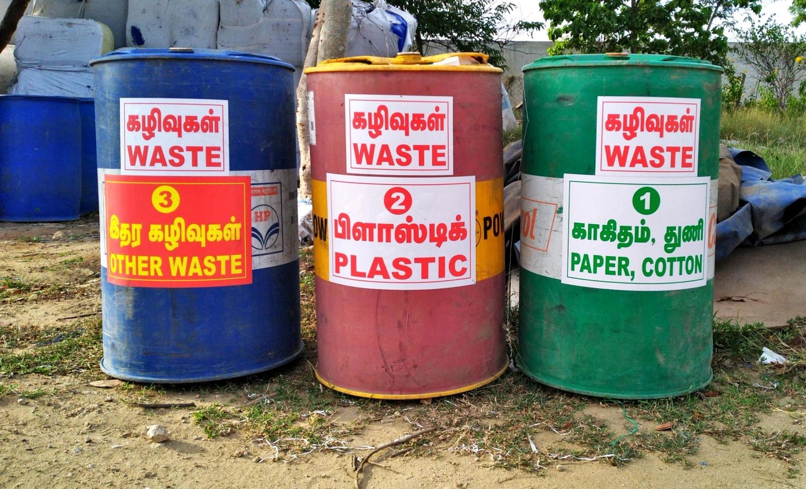 Color-coded waste barrels labelled other waste, plastic, and paper/cotton.